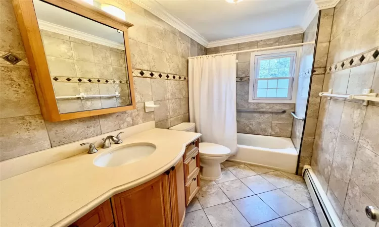 Full bathroom with shower / bath combo, a baseboard heating unit, crown molding, vanity, and tile walls