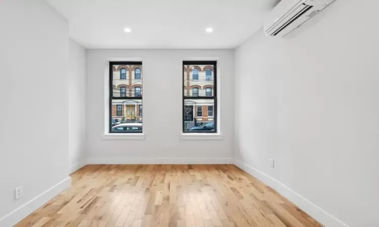 Unfurnished room featuring an AC wall unit and light hardwood / wood-style flooring