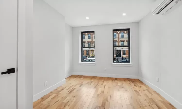 Spare room with a wall mounted AC and light hardwood / wood-style flooring