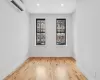 Empty room with a wall unit AC and light hardwood / wood-style floors