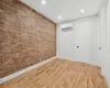 Spare room with a wall unit AC, brick wall, and light hardwood / wood-style floors