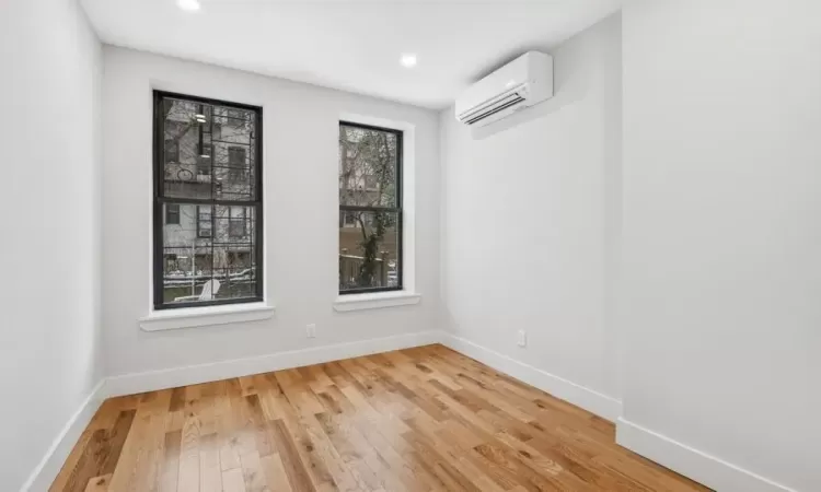 Unfurnished room featuring hardwood / wood-style flooring and a wall mounted AC