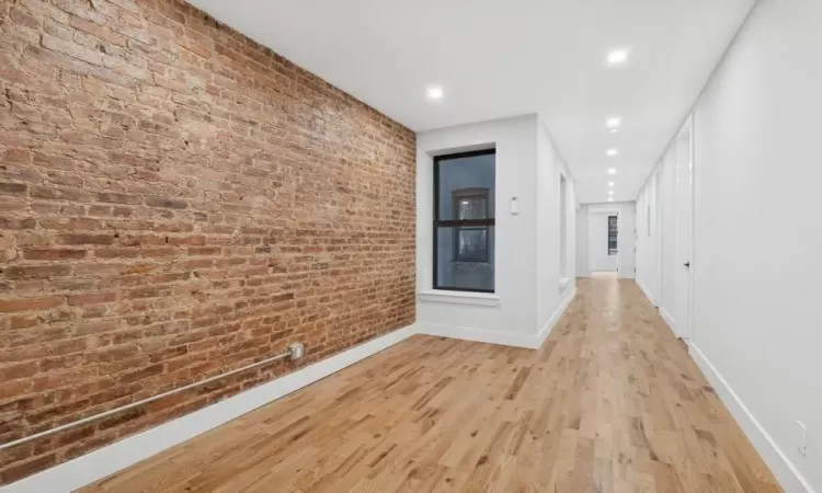 Hall with brick wall and light hardwood / wood-style flooring