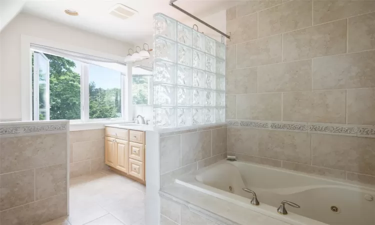 Bathroom with tile patterned flooring, vanity, tile walls, and tiled tub