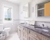 Bathroom featuring tile patterned floors, vanity, tile walls, toilet, and a shower with shower door