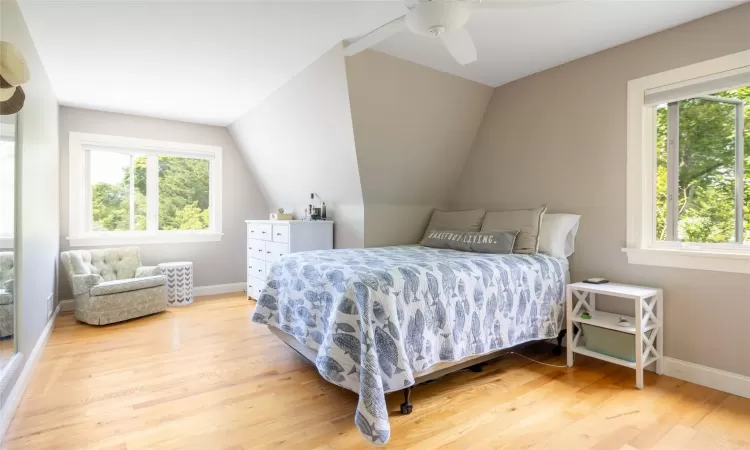 Bedroom featuring hardwood / wood-style floors, ceiling fan, vaulted ceiling, and multiple windows