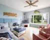 Living room with light hardwood / wood-style floors, a wood stove, and ceiling fan