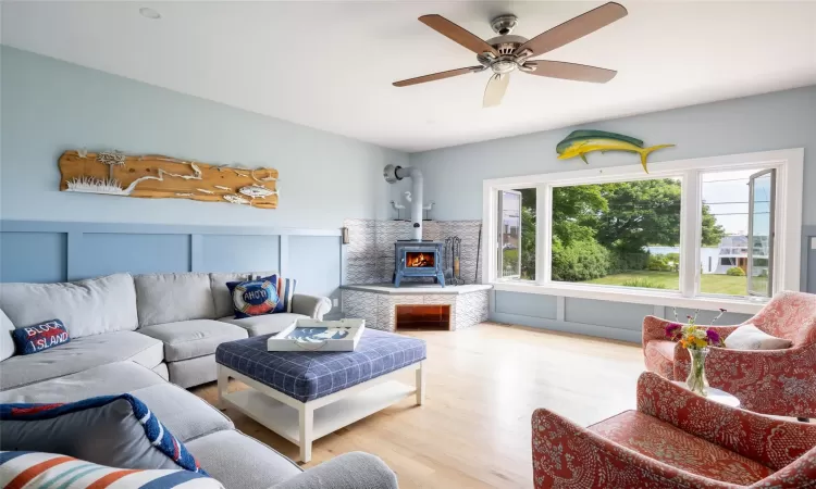 Living room with light hardwood / wood-style floors, a wood stove, and ceiling fan