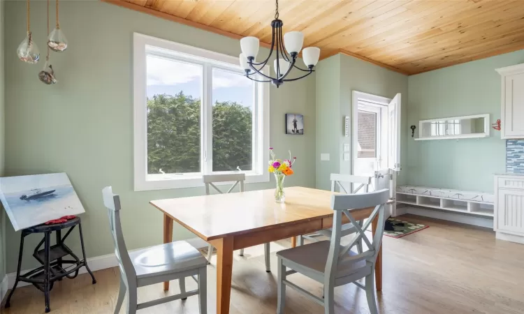 Dining area with crown molding, a chandelier, light hardwood / wood-style flooring, and wood ceiling