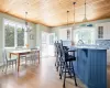 Kitchen with light stone countertops, decorative backsplash, white cabinetry, and wood ceiling