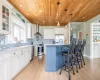 Kitchen featuring white cabinets, decorative light fixtures, wall chimney range hood, and appliances with stainless steel finishes