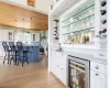 Bar with light stone countertops, white cabinetry, and beverage cooler