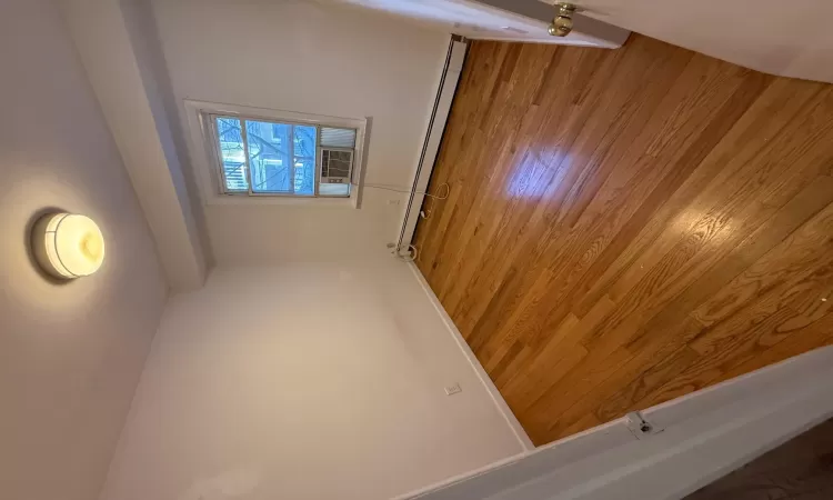 Unfurnished room featuring cooling unit, a baseboard radiator, and wood-type flooring