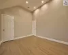 Unfurnished room featuring light wood-type flooring and high vaulted ceiling