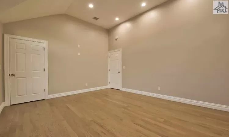 Unfurnished room featuring light wood-type flooring and high vaulted ceiling