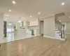 Kitchen with stainless steel dishwasher, crown molding, wall chimney range hood, light hardwood / wood-style flooring, and white cabinetry