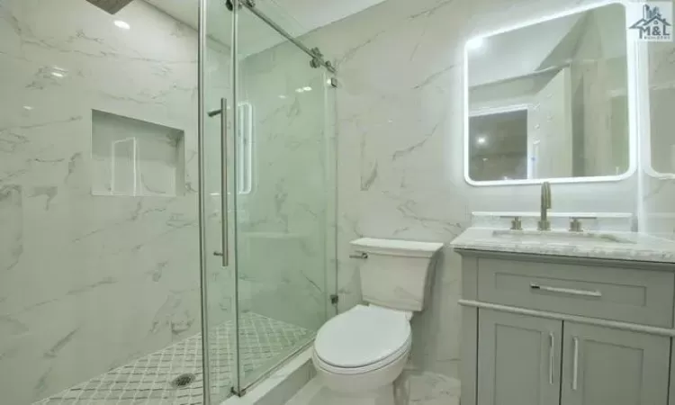 Bathroom featuring toilet, vanity, and walk in shower