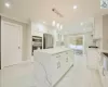 Kitchen featuring decorative backsplash, stainless steel appliances, white cabinets, a center island, and hanging light fixtures