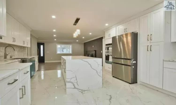 Kitchen featuring white cabinets, sink, hanging light fixtures, light stone countertops, and stainless steel appliances