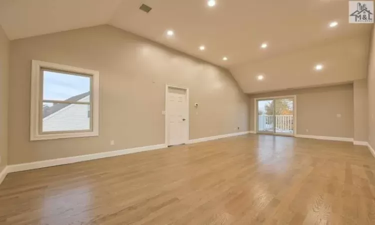 Unfurnished living room with high vaulted ceiling and light wood-type flooring