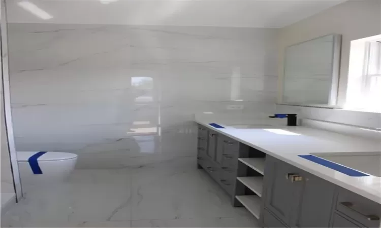 Bathroom with vanity, toilet, and tile walls