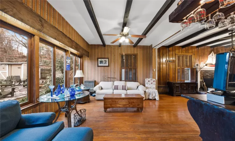 Living room featuring beamed ceiling, hardwood / wood-style flooring, ceiling fan, and a healthy amount of sunlight