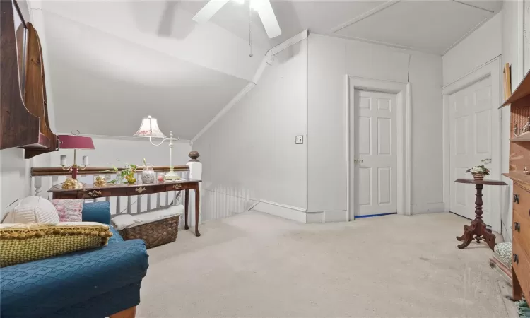 Living area featuring ceiling fan, carpet, lofted ceiling, and ornamental molding