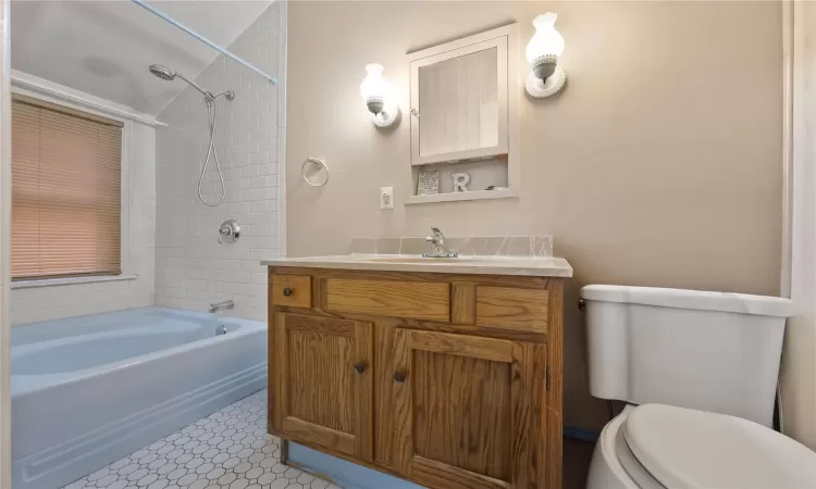 Full bathroom with toilet, vanity, tiled shower / bath combo, and tile patterned flooring