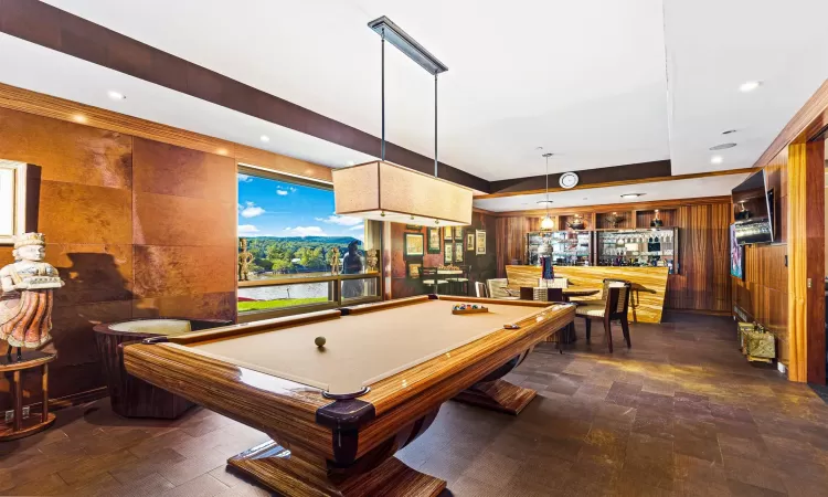 Game room featuring a raised ceiling, wooden walls, indoor bar, and pool table