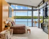 Carpeted bedroom with access to exterior, a water view, a wall of windows, and wooden walls