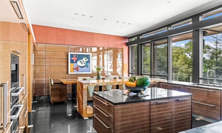 Kitchen featuring a center island, dark stone counters, dark brown cabinets, and sink