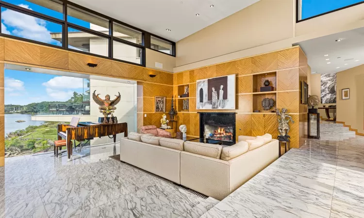 Living room with a fireplace, a towering ceiling, and a water view