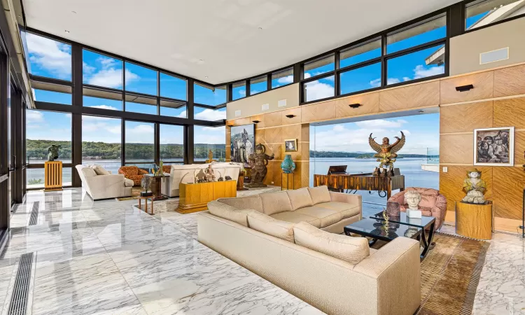 Living room featuring wood walls, a water view, and a high ceiling