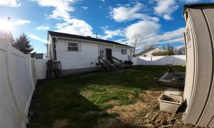 Rear view of house with a yard and a wooden deck