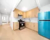 Kitchen featuring sink, light brown cabinets, stainless steel appliances, range hood, and light hardwood / wood-style floors