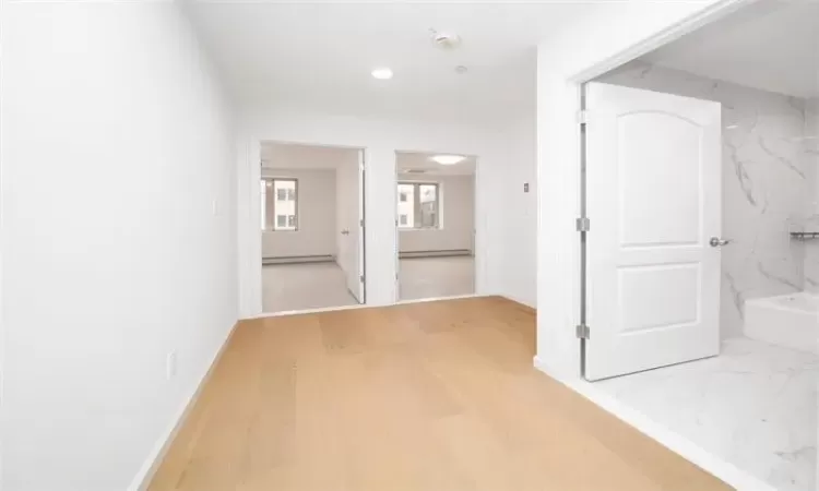 Hallway with hardwood / wood-style floors and a baseboard heating unit