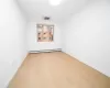 Unfurnished room featuring hardwood / wood-style floors and baseboard heating