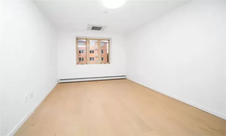 Unfurnished room featuring hardwood / wood-style floors and baseboard heating