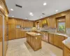 Kitchen with light stone countertops, a center island, stainless steel appliances, light tile patterned floors, and custom exhaust hood