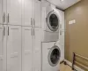 Laundry area with cabinets, stacked washing maching and dryer, and light tile patterned floors