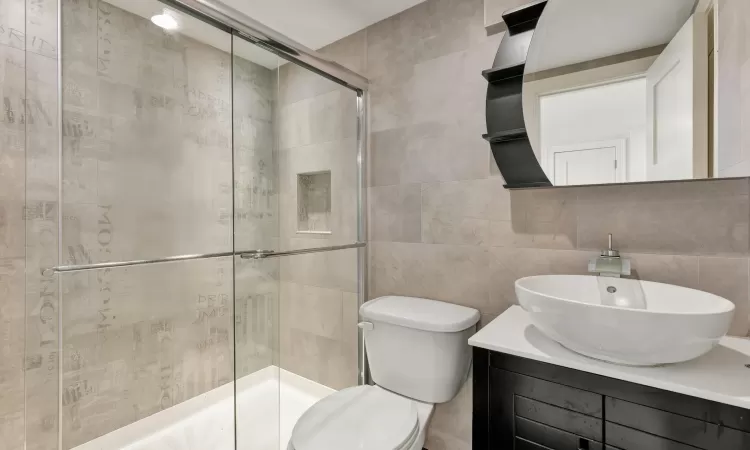 Bathroom with vanity, toilet, tile walls, walk in shower, and tasteful backsplash