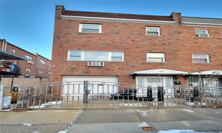 View of building exterior with a garage and a wall mounted AC