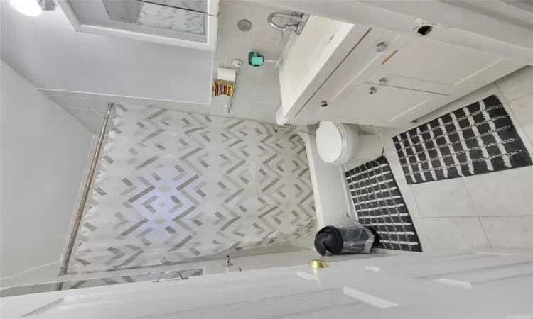 Bathroom featuring tile patterned floors, vanity, tile walls, and toilet