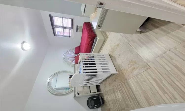 Bedroom with a wall mounted air conditioner and light hardwood / wood-style flooring