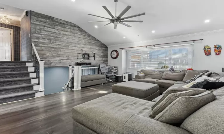 Living room featuring ceiling fan, crown molding, dark wood-type flooring, and vaulted ceiling