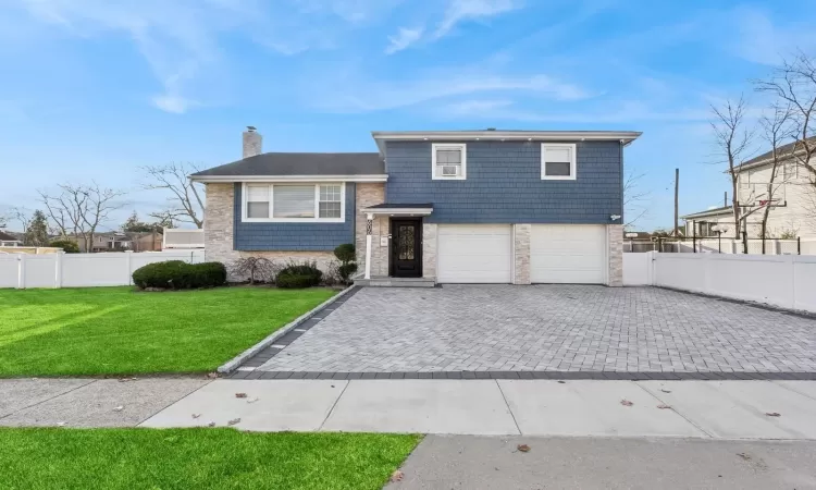 View of front facade featuring a front lawn and a garage