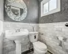 Bathroom featuring toilet and tile walls