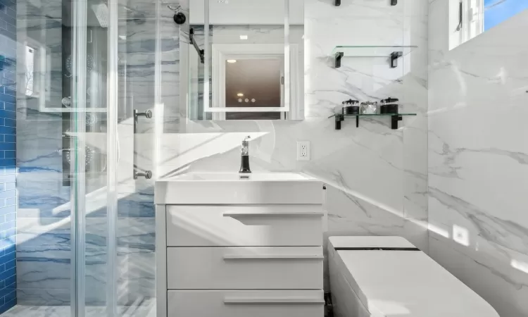 Bathroom featuring vanity, an enclosed shower, and decorative backsplash