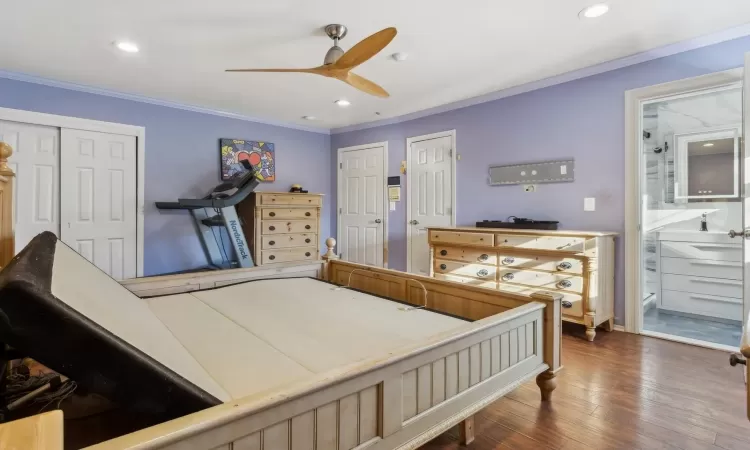 Bedroom featuring connected bathroom, dark hardwood / wood-style floors, ceiling fan, and crown molding