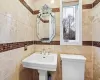 Bathroom featuring sink, tile walls, and toilet